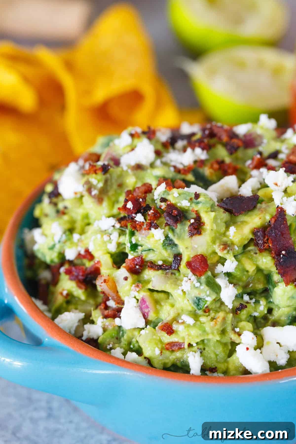 Smoked Poblano and Black Pepper Bacon Guac 5 A generous serving of ultimate loaded guacamole, garnished with extra bacon and queso fresco, accompanied by a glass of chilled sweet wine, ready for a party.