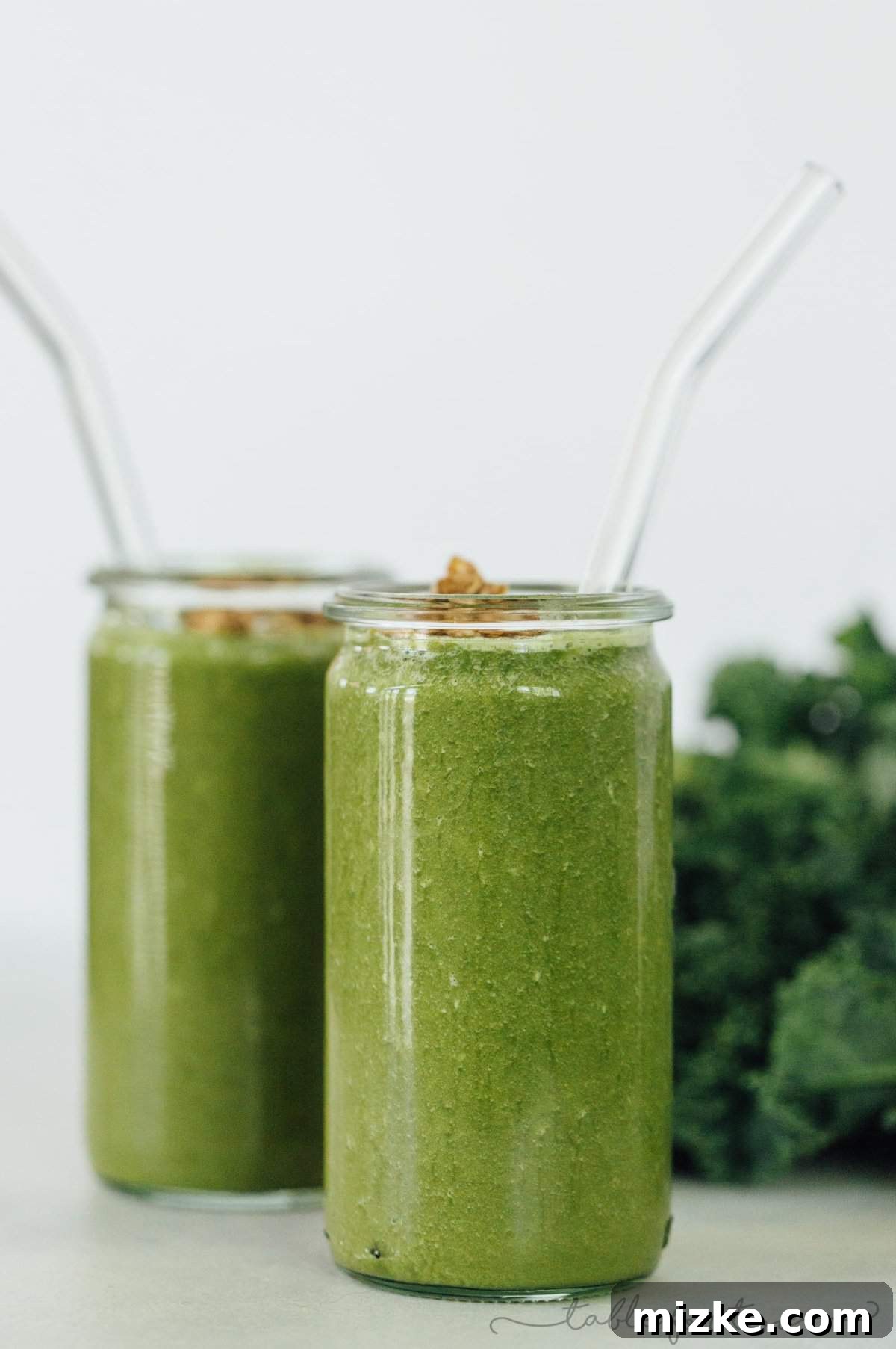 A vibrant green smoothie in a glass, showcasing the healthy and tropical blend of the TropiKale recipe.