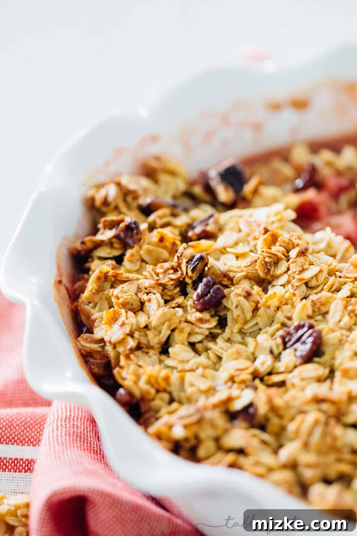 Close-up of a freshly baked Strawberry Mint Crisp, showcasing the bubbling strawberry and mint filling beneath a golden, textured crisp topping. The aroma of this homemade summer dessert is almost palpable.