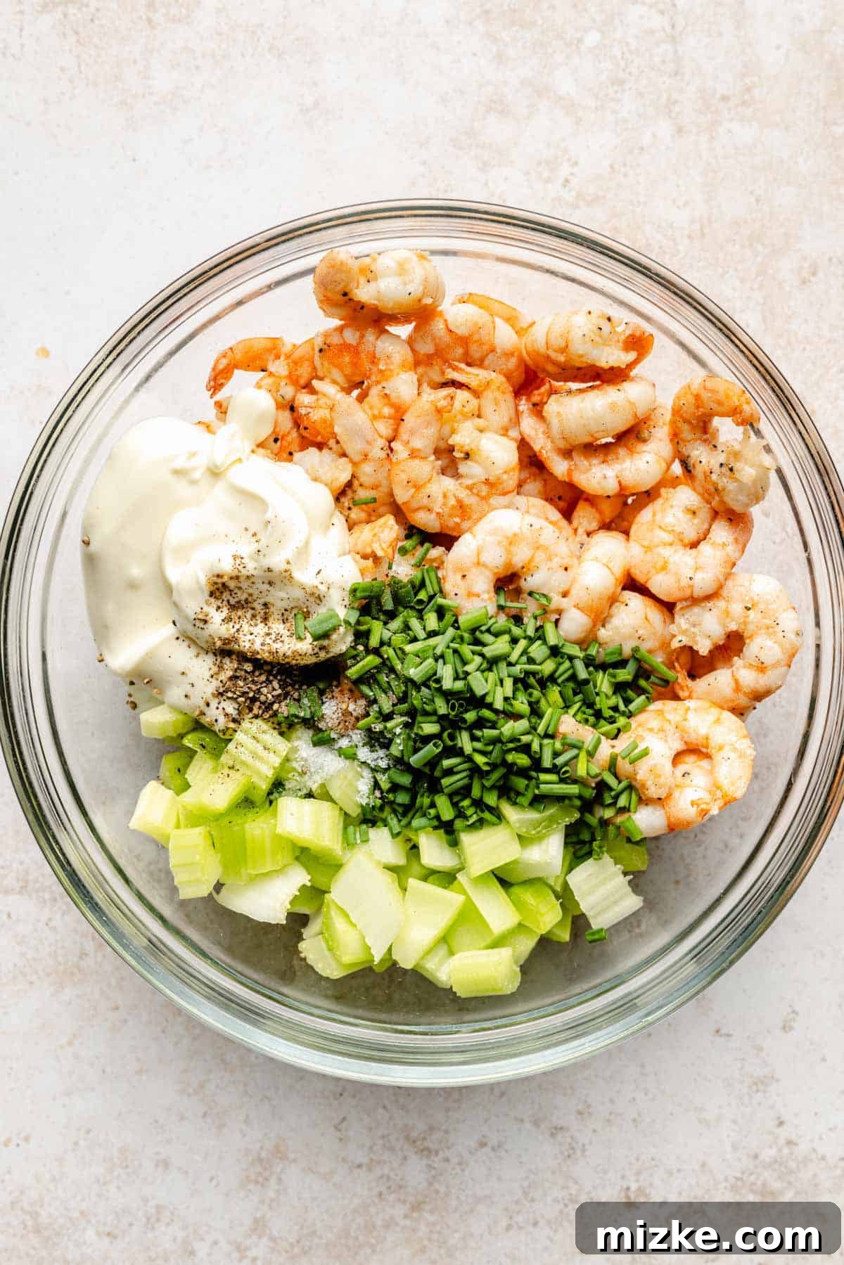 Savory Shrimp Wraps 6 A clear glass bowl filled with a vibrant mixture of cooked shrimp, creamy mayonnaise, crisp celery, fresh chives, and bright lemon juice, perfectly blended for the roll filling.