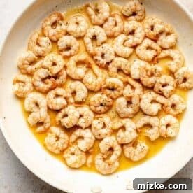 Shrimp being cooked in a skillet with butter until perfectly pink and opaque.