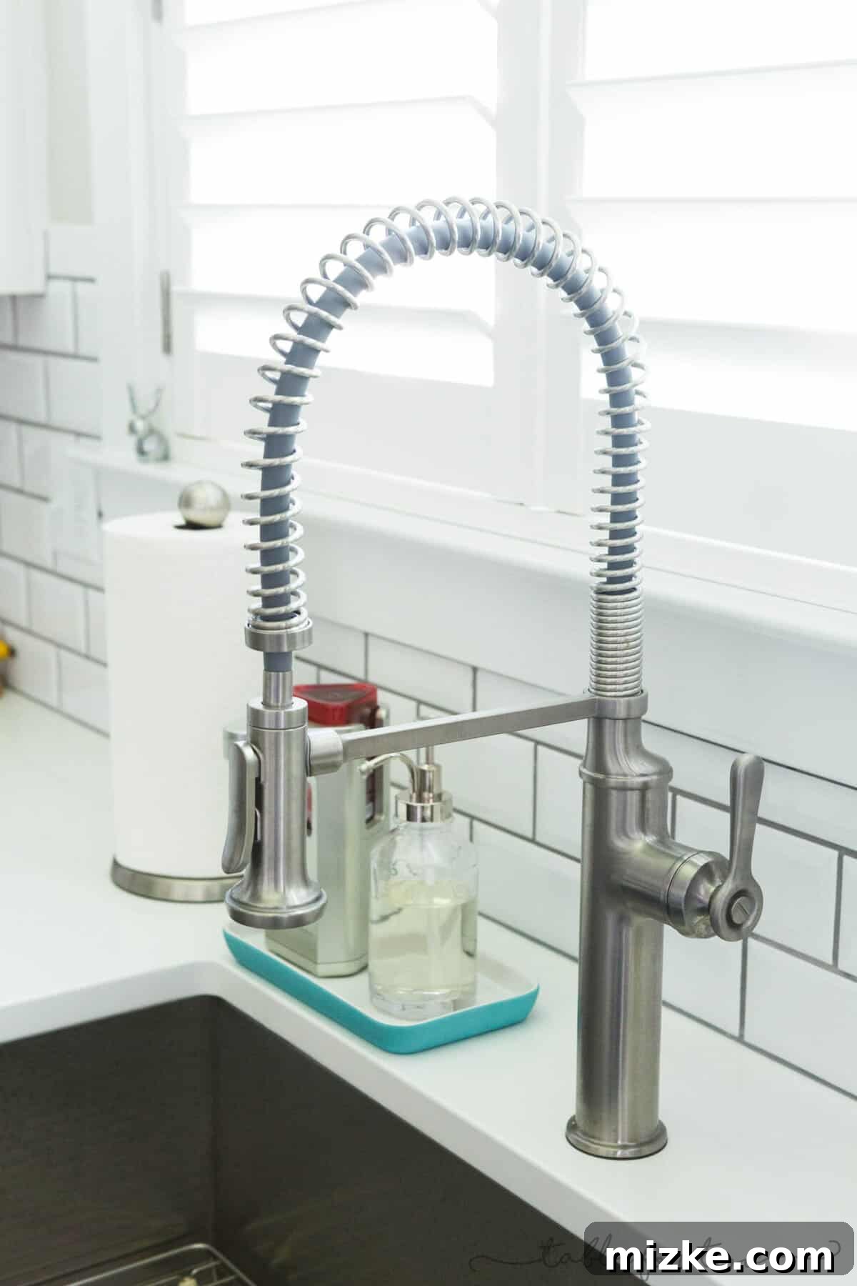 Welcome to My Kitchen 4 Close-up of a large stainless steel apron front sink with a modern pull-down faucet, emphasizing functionality and style.