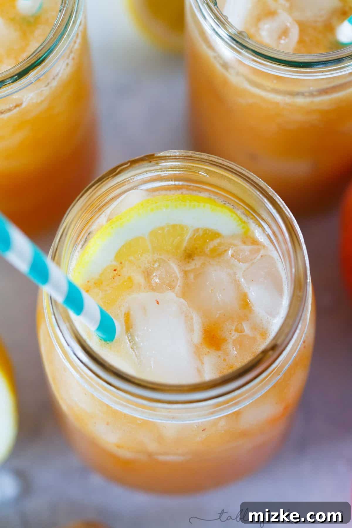 Peach Ginger Lemon Fizz 3 Close-up of a refreshing Lemon Ginger Peach Spritzer with abundant crushed ice, showcasing the beautiful peach puree and a vibrant lemon slice garnish, ready to hydrate and delight.