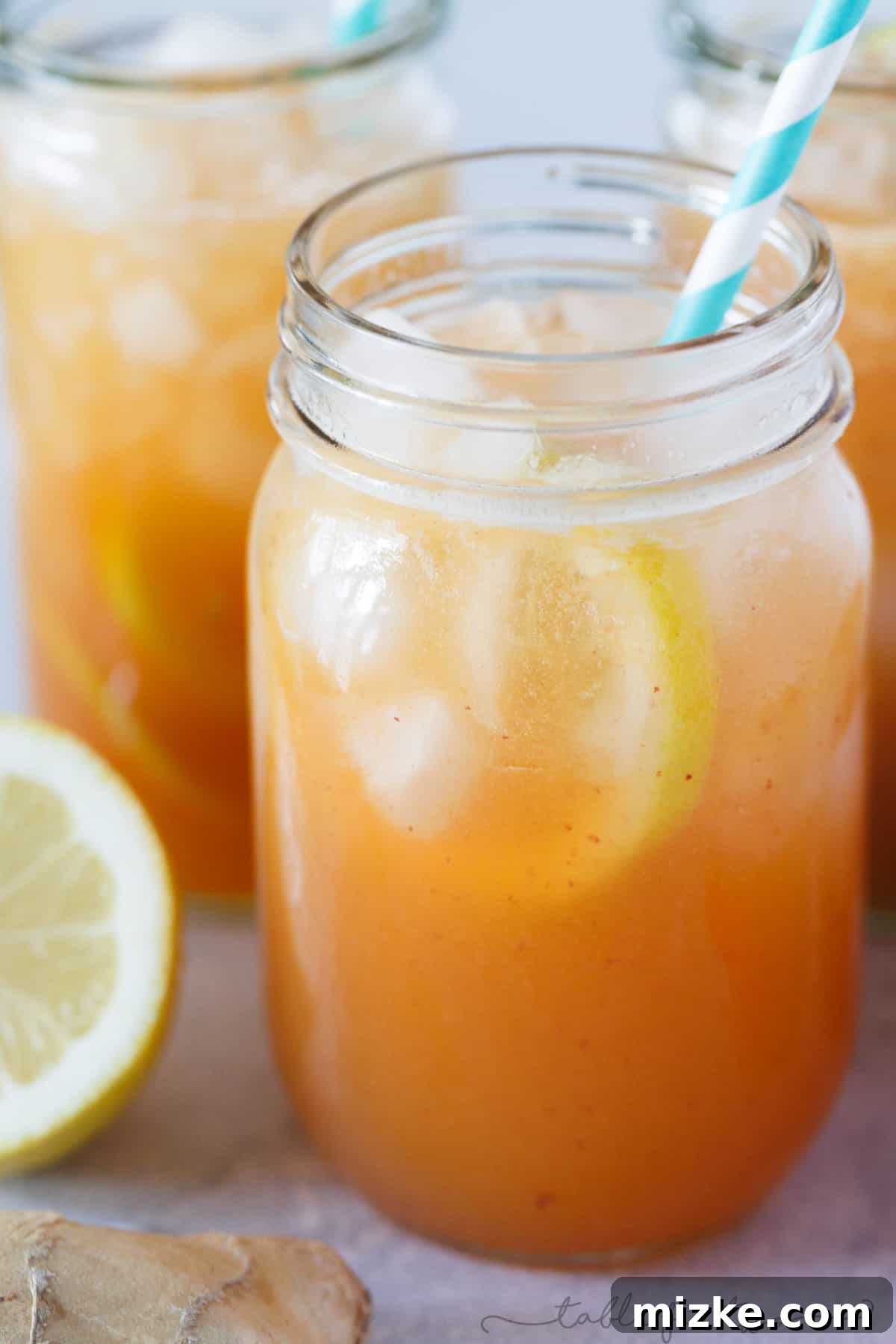 Peach Ginger Lemon Fizz 4 Overhead shot of two glasses of Lemon Ginger Peach Spritzer, elegantly garnished, surrounded by fresh, ripe peaches, bright lemon halves, and aromatic ginger root on a clean white surface, showcasing the natural ingredients.