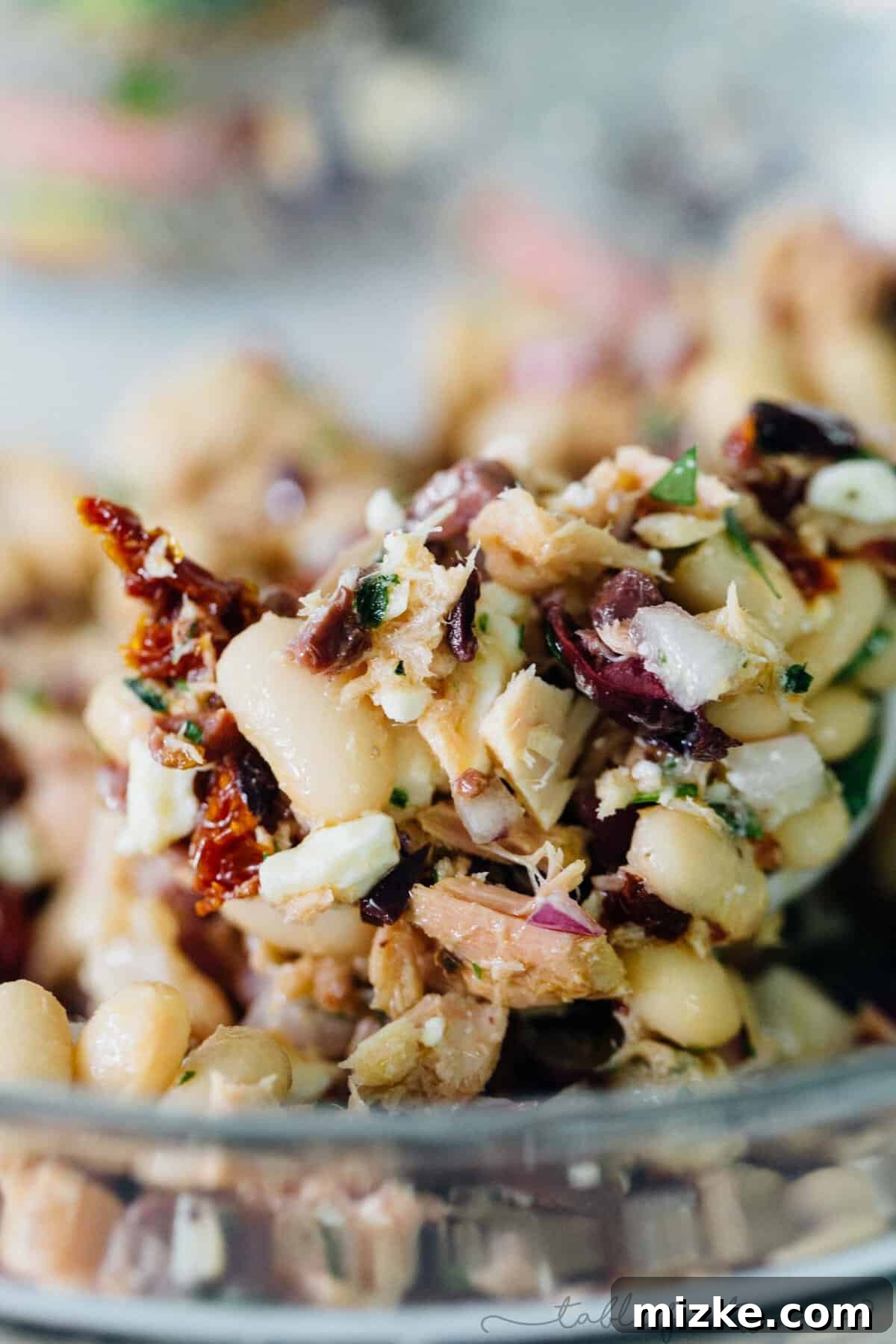 Bright Mediterranean Tuna & White Bean Salad 5 A serving of Mediterranean tuna white bean salad piled high on a piece of crusty bread, showcasing a delicious way to enjoy the dish.