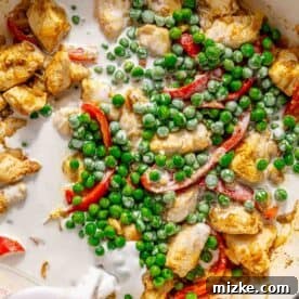 Spicy Thai Green Curry Chicken Rice Bowl 10 A pot of green chicken curry with coconut milk being poured in, featuring pieces of chicken, green peas, and red bell peppers.