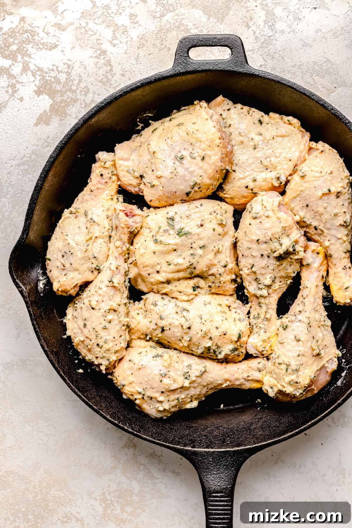 Caramelized Fig Chicken Skillet 5 Uncooked bone-in chicken pieces (drumsticks and thighs) are generously coated with the fragrant garlic herb butter mixture in a cast iron skillet.