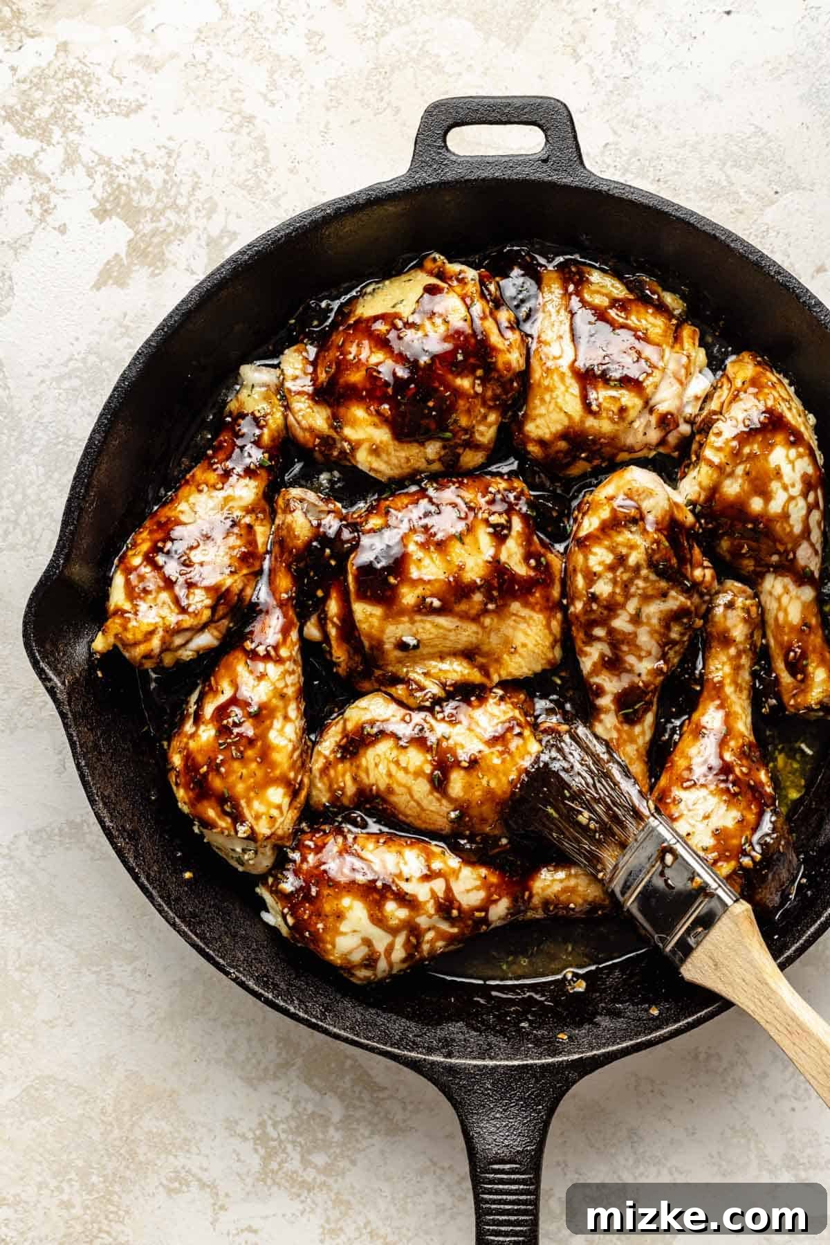 Caramelized Fig Chicken Skillet 7 Perfectly roasted chicken pieces in a cast iron skillet are being brushed with the rich, sticky fig balsamic glaze, creating a beautiful shine.