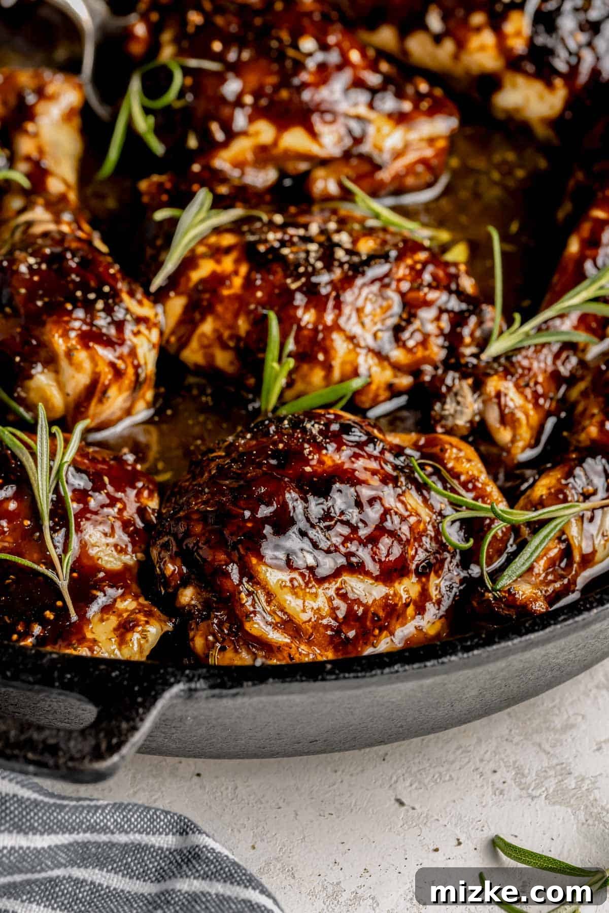 Caramelized Fig Chicken Skillet 8 A close-up of a beautifully fig glazed chicken piece, garnished with fresh rosemary, highlighting the sticky glaze and herbs.
