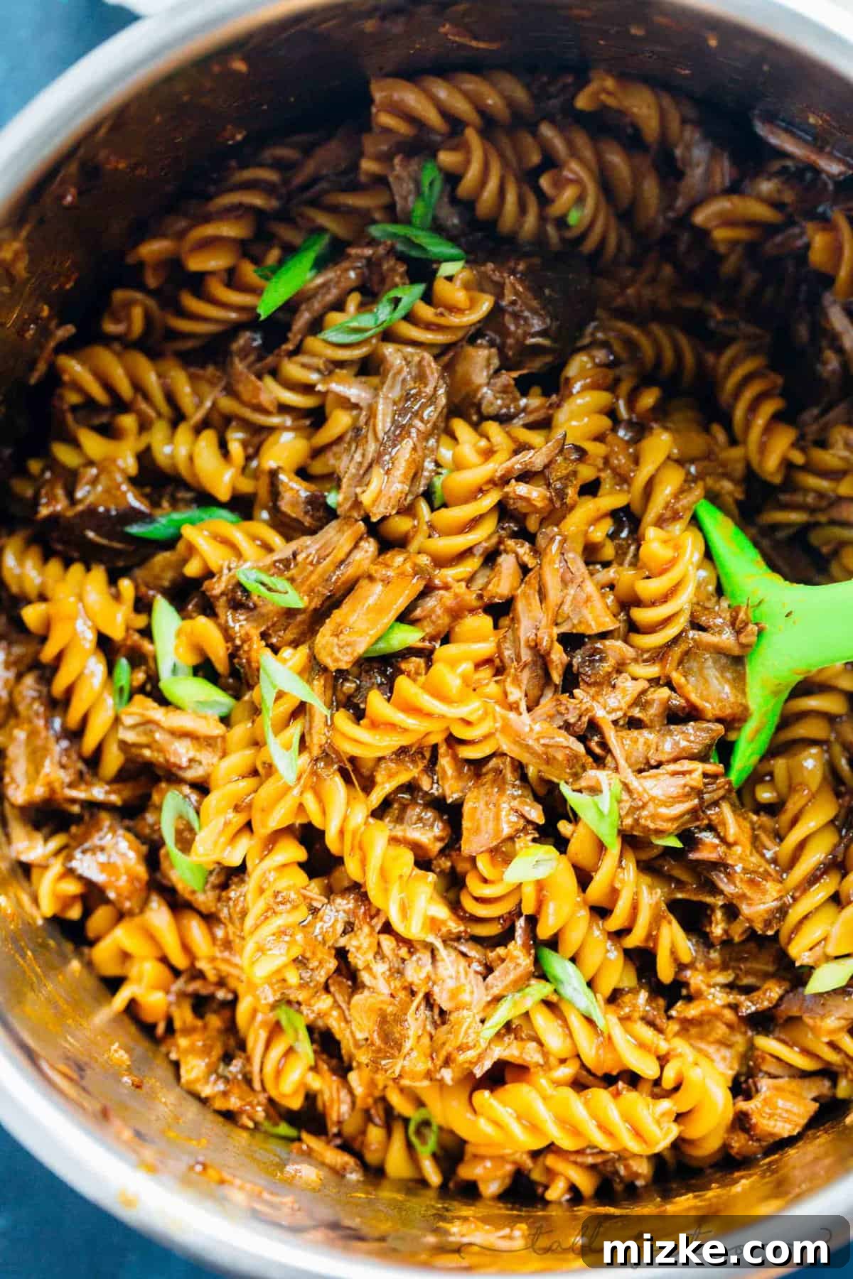 Tender Korean Beef Ragu 5 A serving of Pressure Cooker Braised Korean Beef Ragu with shredded beef and rotini pasta, presented in a rustic bowl, ready to be enjoyed.