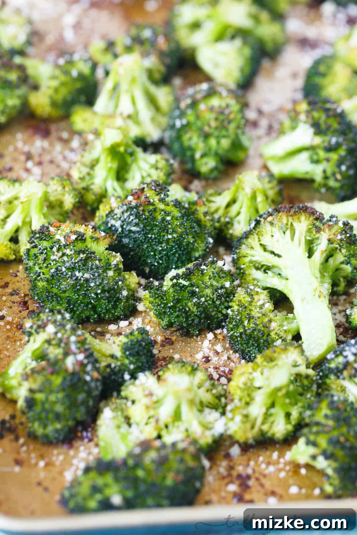 Parmesan-Crusted Roasted Broccoli 3 A vibrant pile of freshly roasted parmesan broccoli on a white plate, showcasing its appealing texture and cheesy coating.