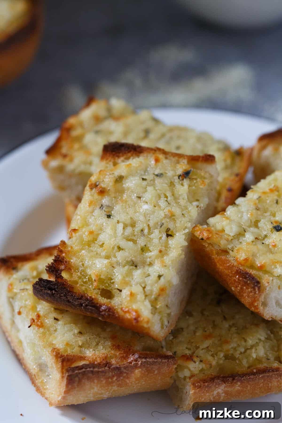 Epic Garlic and Parmesan Cheese Bread 4 Individual slices of the decadent garlic bread, featuring a thick layer of melted cheese and herbs, ready for serving.