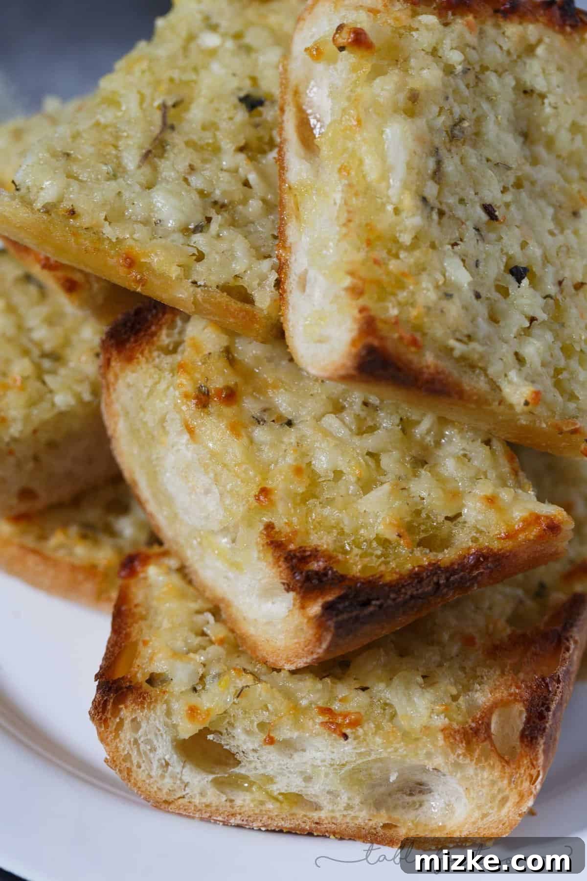 Epic Garlic and Parmesan Cheese Bread 5 A delicious stack of freshly baked extra garlicky and cheesy bread slices on a serving board.