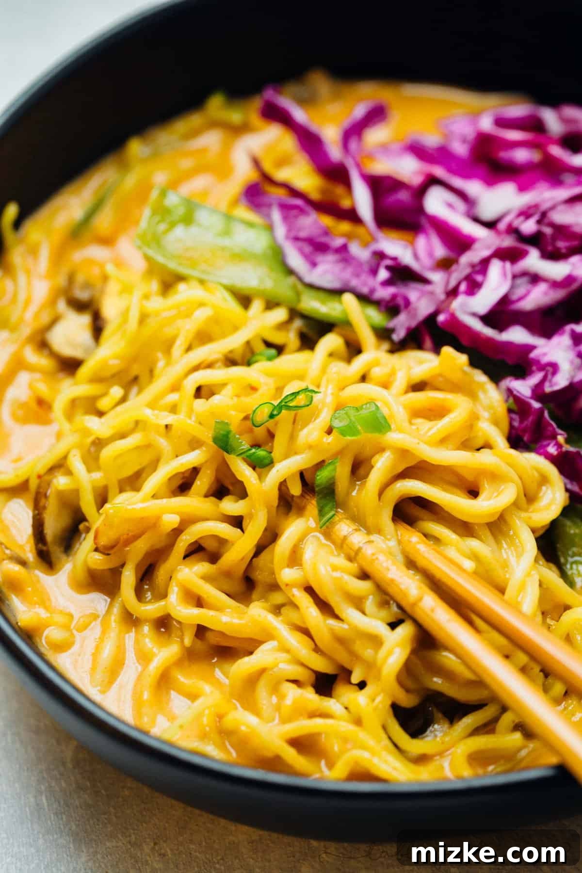 Luscious Coconut Curry Ramen 5 Dynamic action shot of tender ramen noodles being pulled from a deeply flavored, steaming coconut curry broth, highlighting their irresistible texture.