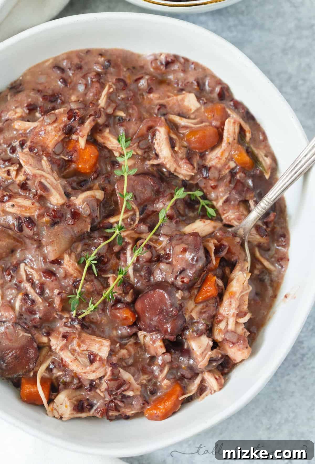 Velvety Instant Pot Chicken Mushroom Wild Rice Stew 5 A spoon lifting a generous portion of Instant Pot creamy mushroom and chicken wild rice stew from a serving bowl, showcasing its delicious layers.