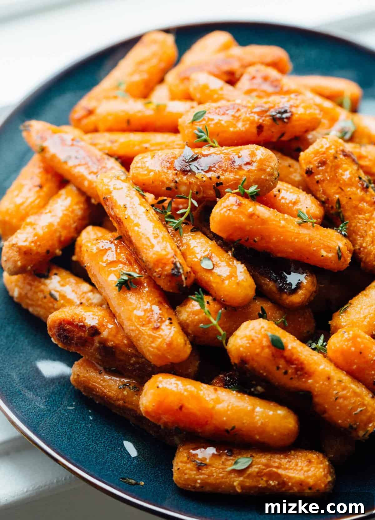 Parmesan Crusted Roasted Carrots 2 A close-up of beautifully roasted parmesan carrots, golden and tender, sprinkled with fresh thyme, ready to be served.