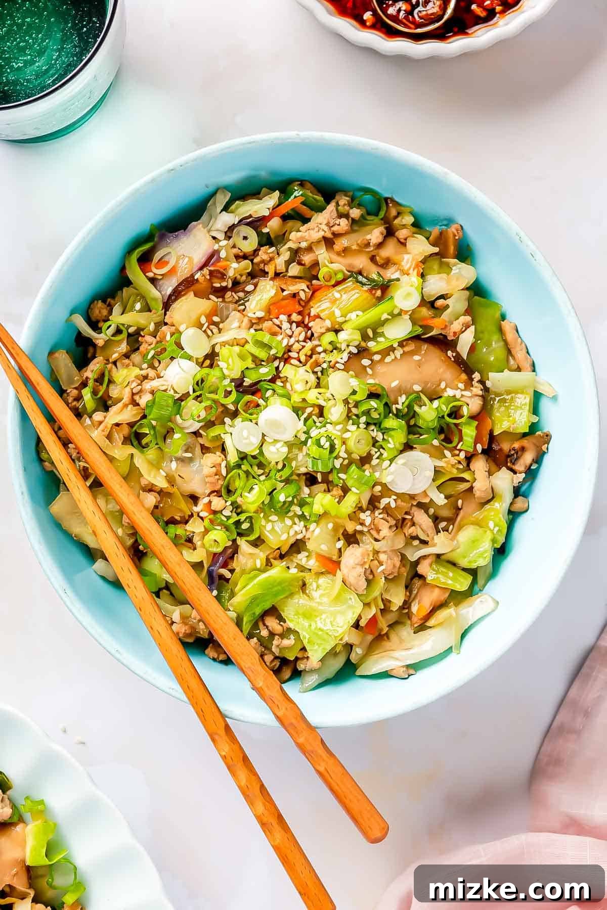 A vibrant egg roll in a bowl served in a blue ceramic bowl, with wooden chopsticks resting on the rim, ready for a delicious meal.