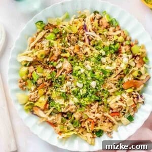 eggroll filling on a scalloped blue plate with fresh scallions and white sesame seeds sprinkled on top