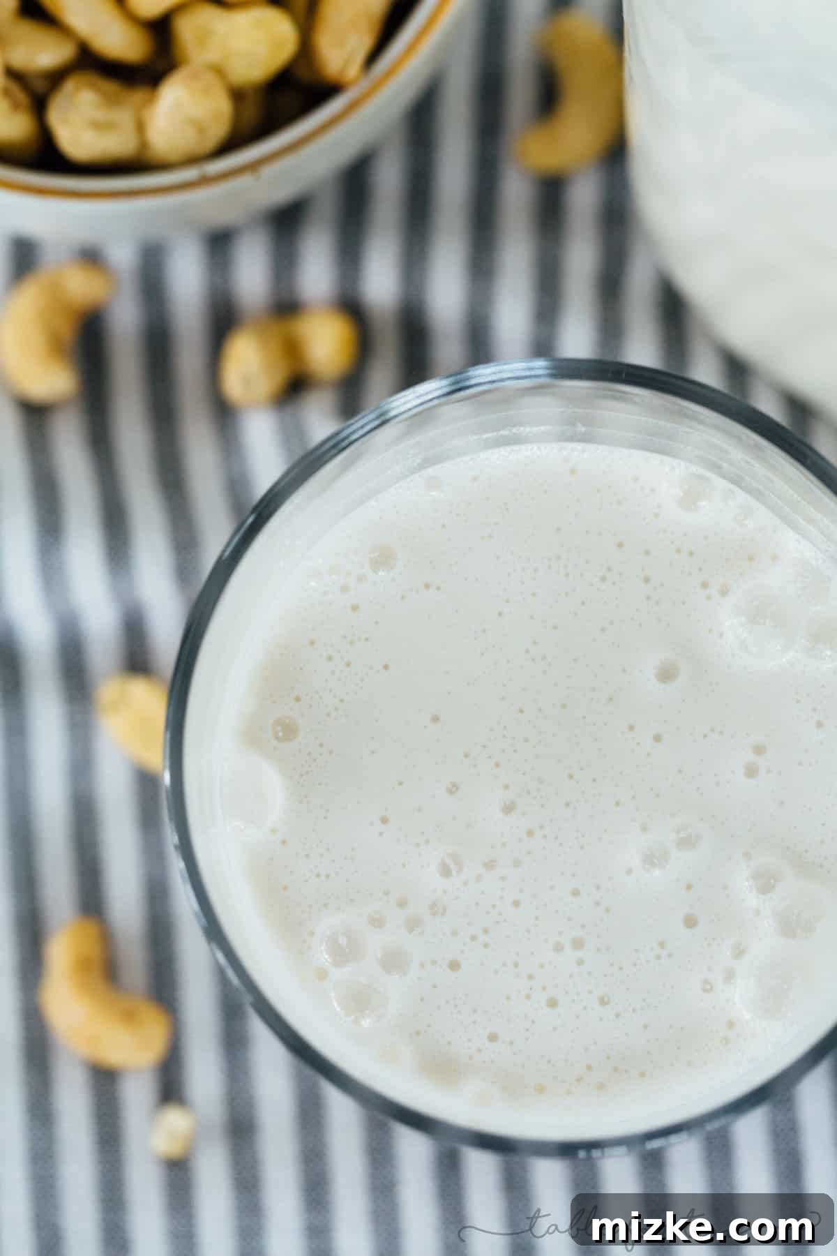 The ease of making fresh, delicious cashew milk at home is unmatched. Overhead view of a clear glass blender carafe filled with soaking raw cashews and fresh water, ready to be transformed into homemade cashew milk. Illustrates the straightforwardness of the preparation.