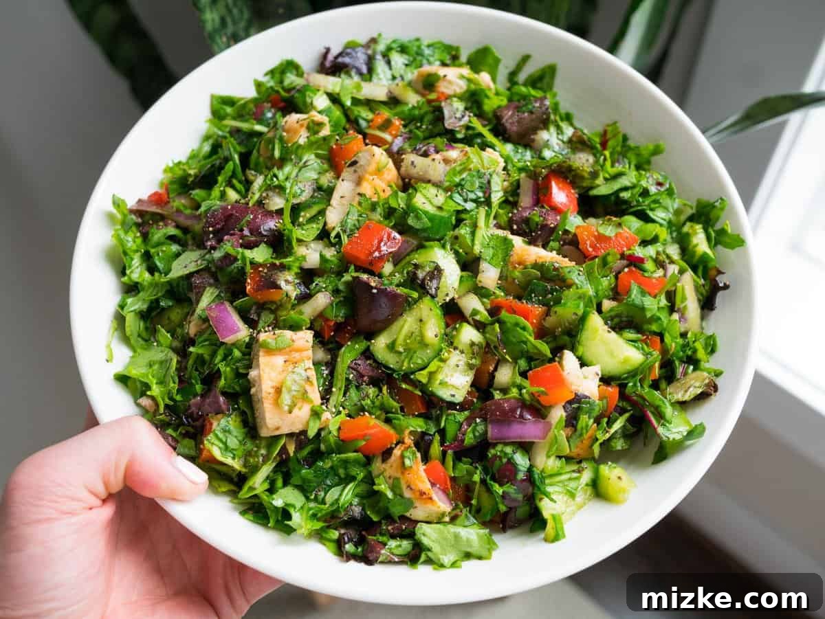 Versatile Chopped Salad: Fresh Greens, Cucumbers, and Olives for Easy Customization Close-up of a refreshing and customizable chopped salad featuring crunchy cucumbers, red onions, and kalamata olives, making it an excellent base for any meal.