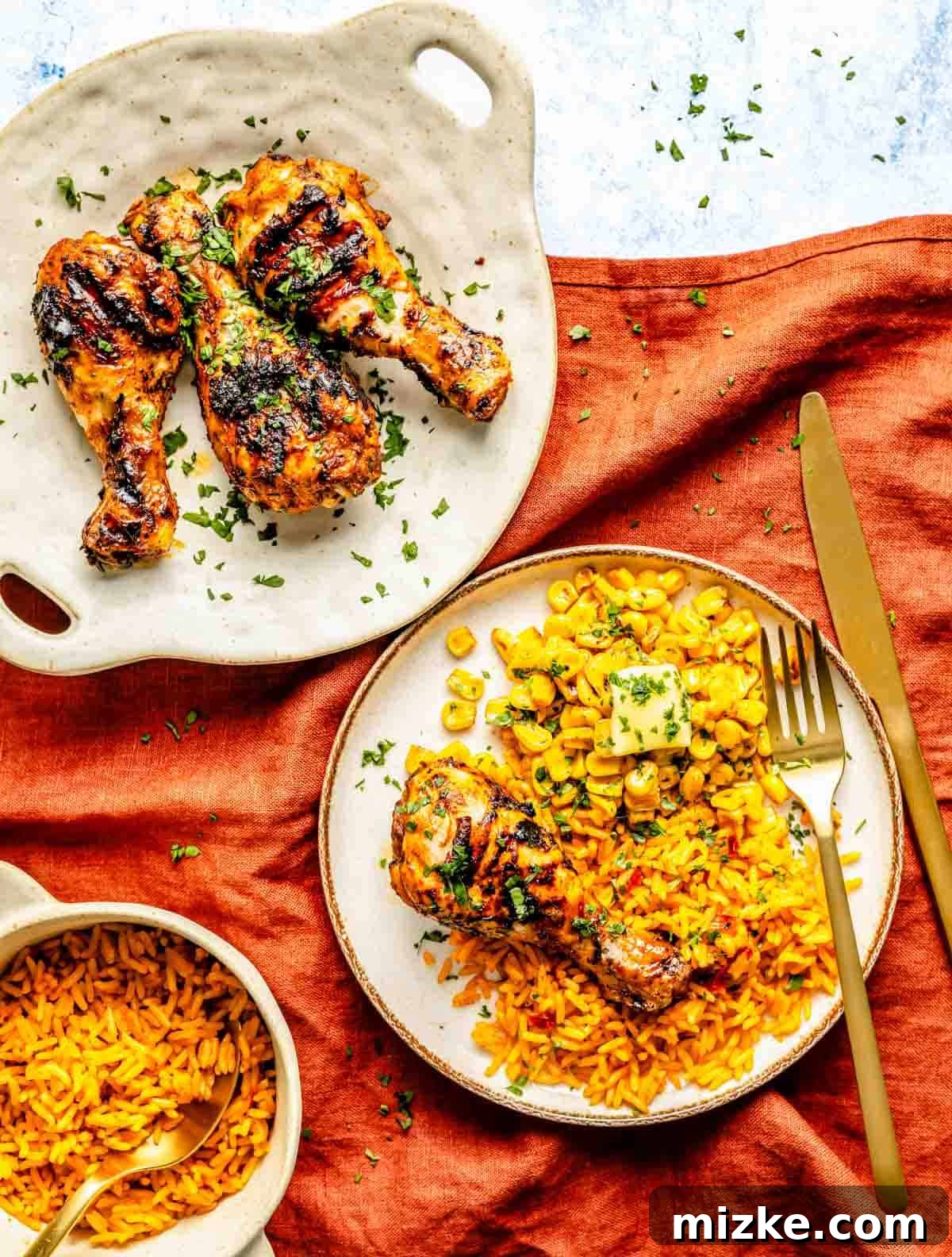 Zesty Peri Peri Chicken Drumsticks 2 Grilled chicken drumsticks on a plate with corn and rice, garnished with herbs, alongside a bowl of rice.