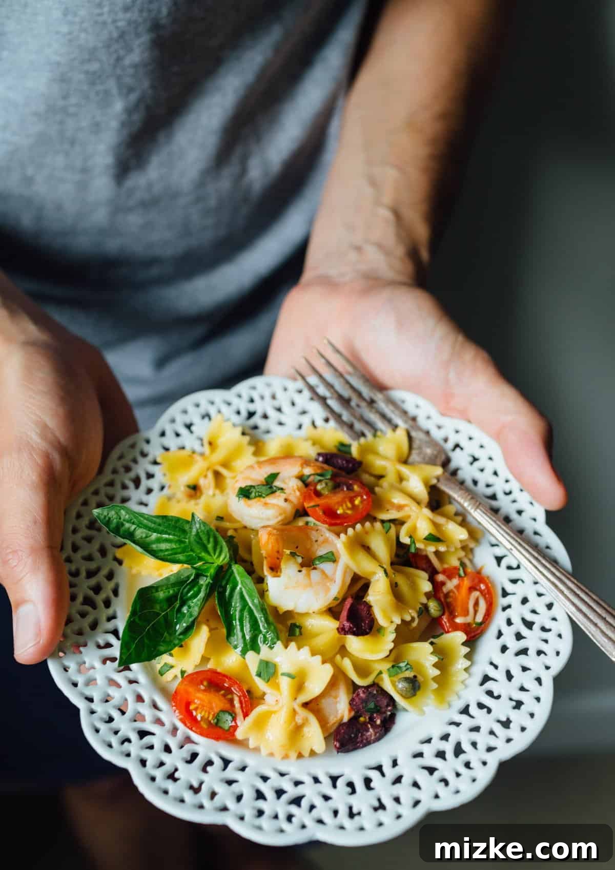 make this light and refreshing pasta dish! It is tossed with olive oil, lemon juice, and shrimp for a fresh and clean tasting Mediterranean dish packed with loads of flavor! A final serving of the Mediterranean Farfalle Toss with Shrimp, garnished with fresh basil, showcasing a perfect balance of pasta, protein, and colorful vegetables.