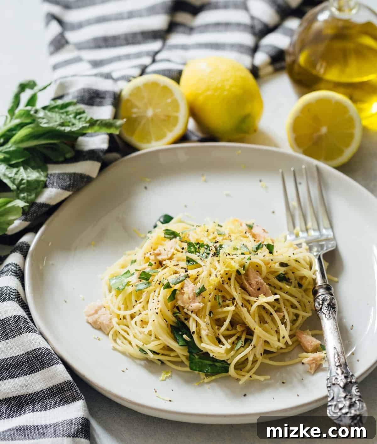 Sunshine Tuna Pasta 3 A close-up view of the delicate angel hair pasta intertwined with flakes of tuna, vibrant lemon zest, and fresh spinach.