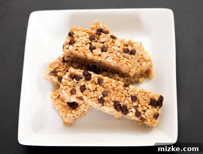 Hearty Chocolate Walnut Granola Bars 3 A close-up shot of two homemade granola bars, showing the rich texture of oats, walnuts, and melted chocolate chips, resting on a white surface.