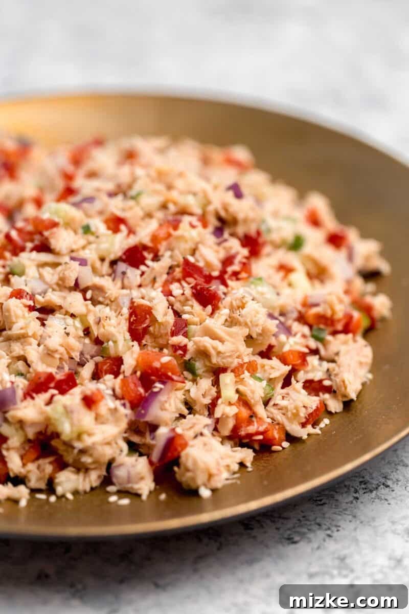 Vibrant Thai Tuna Salad 3 Close-up shot of the fresh ingredients for Thai Tuna Salad – flaked tuna, diced red bell pepper, red onion, and cucumber – being mixed together in a large bowl before adding the dressing.