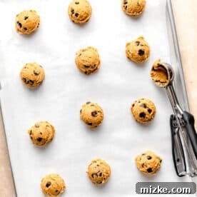 Balls of cookie dough are spread out on a baking sheet