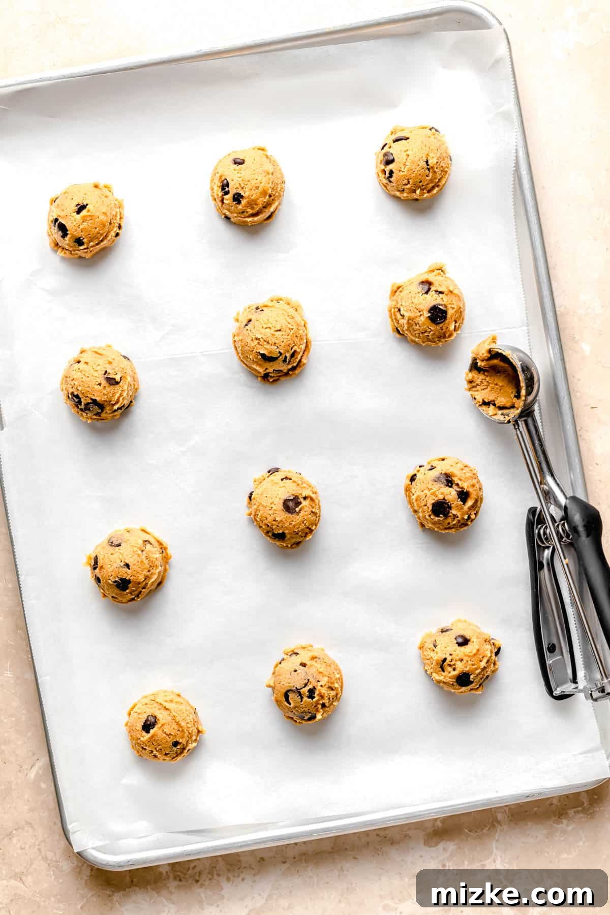Caramelized Butter Chocolate Chip Cookies 8 Perfectly portioned balls of brown butter chocolate chip cookie dough evenly spread out on a parchment-lined baking sheet, ready for the oven.