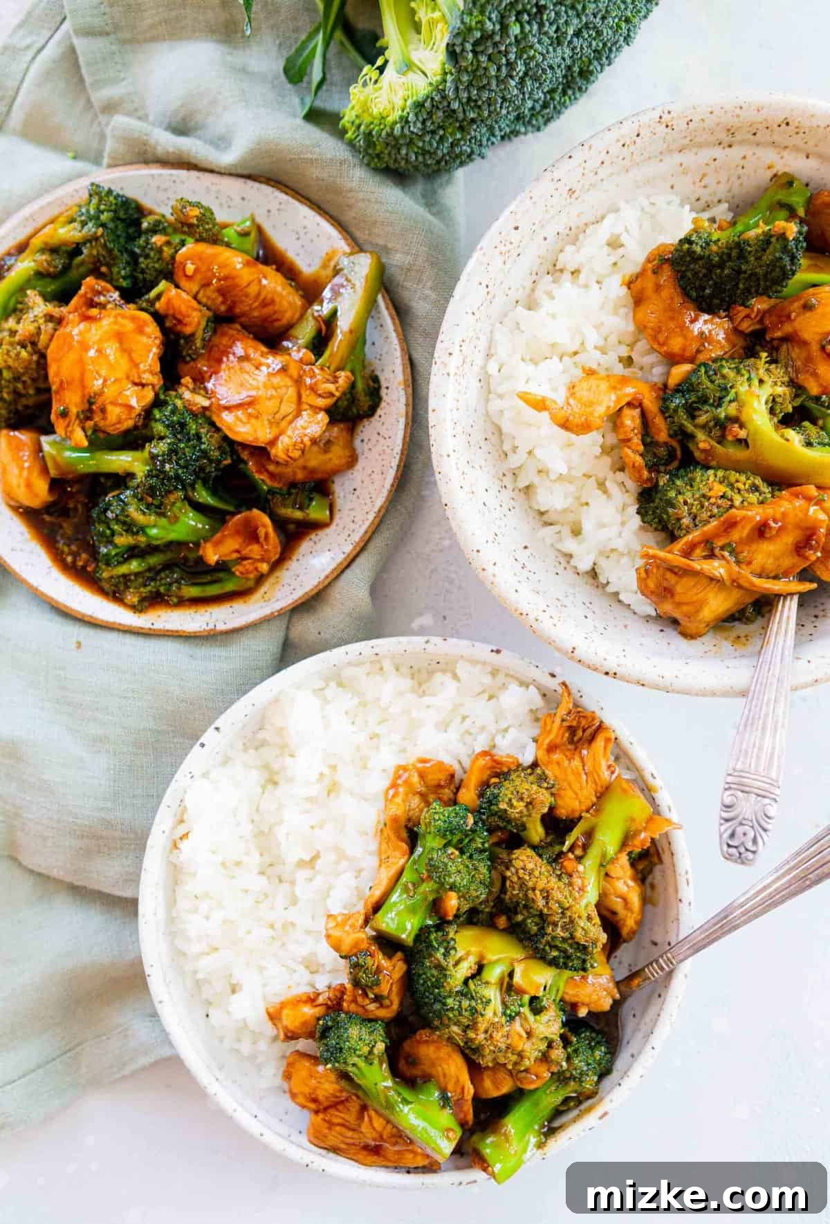 Homemade Chinese Chicken and Broccoli: Tender chicken in savory sauce with crisp broccoli for a perfect takeout fakeout meal! Overhead view of plated Chinese Chicken and Broccoli served in bowls alongside fluffy white rice, ready to be enjoyed.