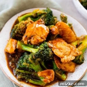 Close-up of Chinese Chicken and Broccoli on a ceramic plate, beautifully plated on a light green linen towel, showcasing the rich sauce and fresh ingredients.