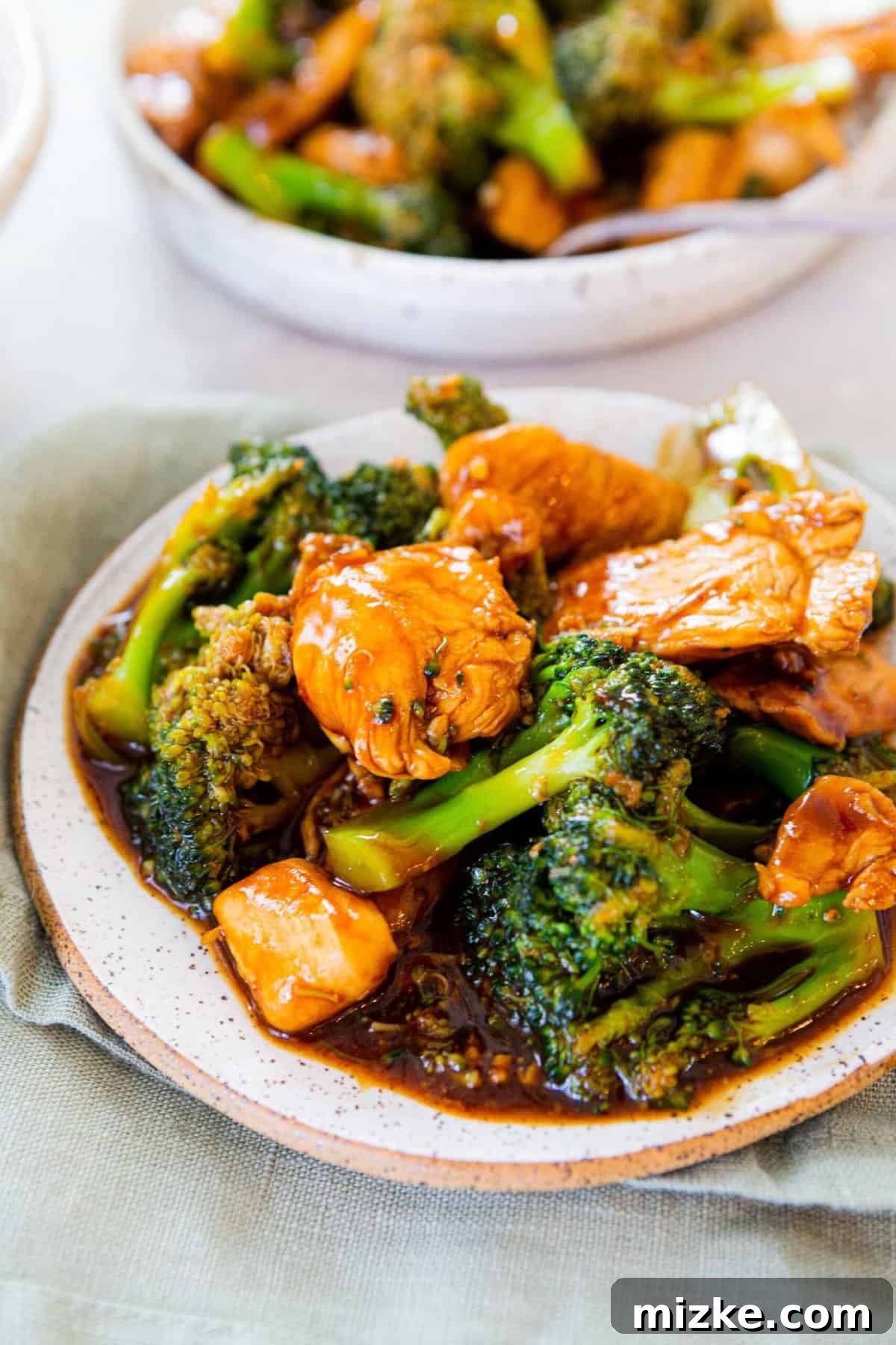 Savory chicken and broccoli in a classic Chinese brown sauce – perfectly delicious and easy to make at home! Close-up of Chinese Chicken and Broccoli with a rich, dark brown sauce served on a speckled white ceramic plate, ready for dining.