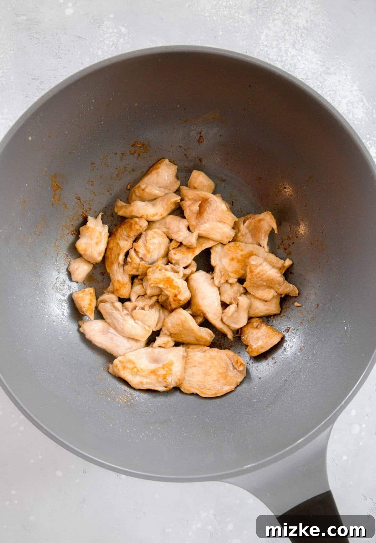 Searing the thinly sliced chicken in a wok for your homemade Chinese Chicken and Broccoli. Thin slices of marinated boneless skinless chicken breast browning in a large, hot wok, developing a delicious golden crust.