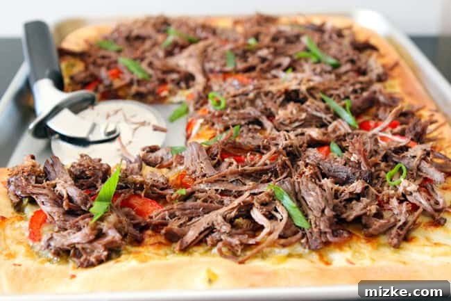 Carnitas Fiesta Pizza 4 A large, juicy slice of Carnitas Pizza being held, showing the thick layer of meat and cheese