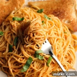 Delicious Roasted Red Pepper Pesto Pasta with goat cheese, garnished with fresh basil.