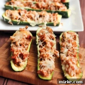 Close-up of a perfectly baked zucchini boat, showing the melted cheese and rich, browned turkey sausage filling.