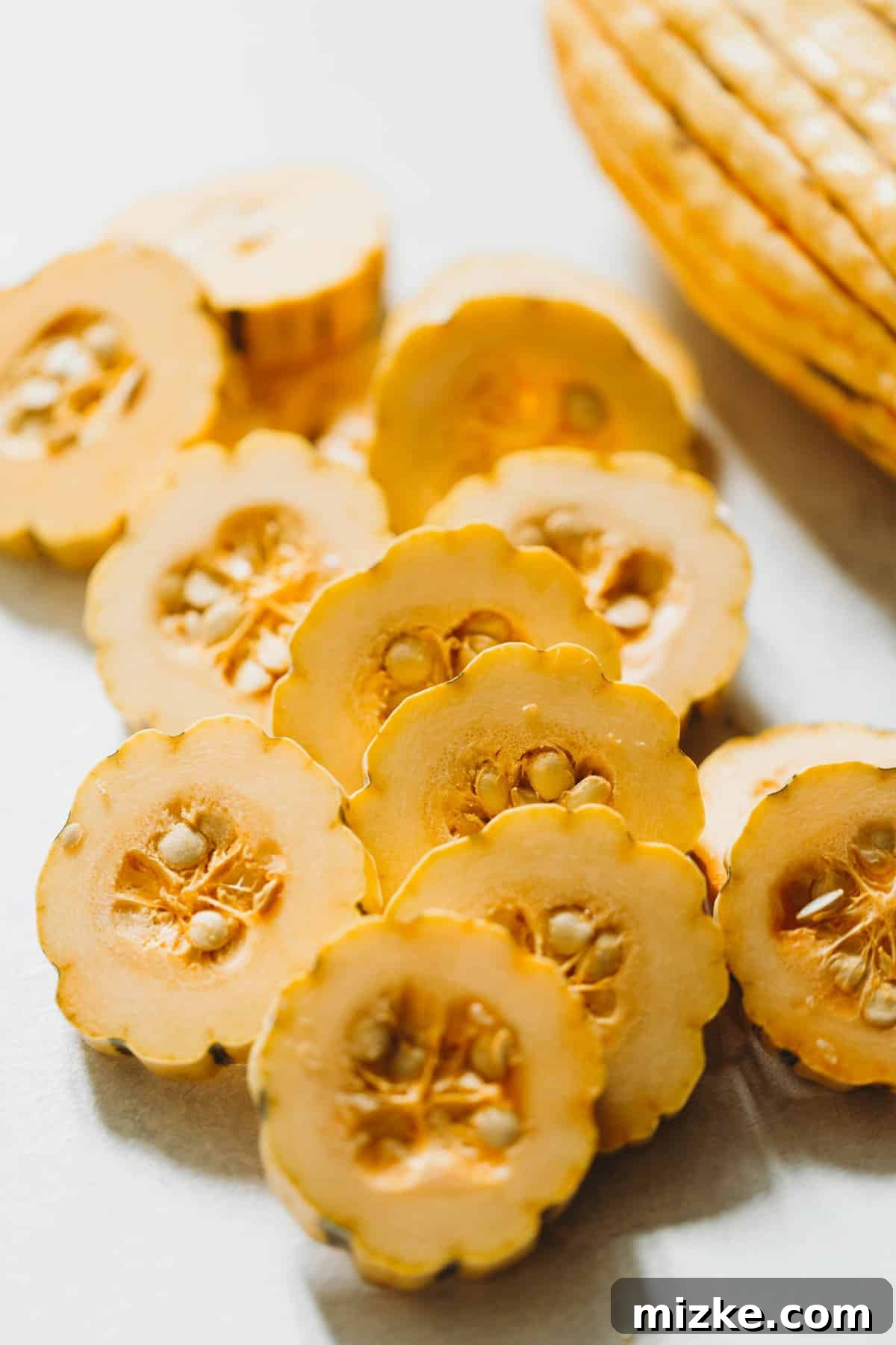 Caramelized Delicata Squash 3 A pile of raw delicata squash slices, cut into half-moon shapes, ready for roasting.