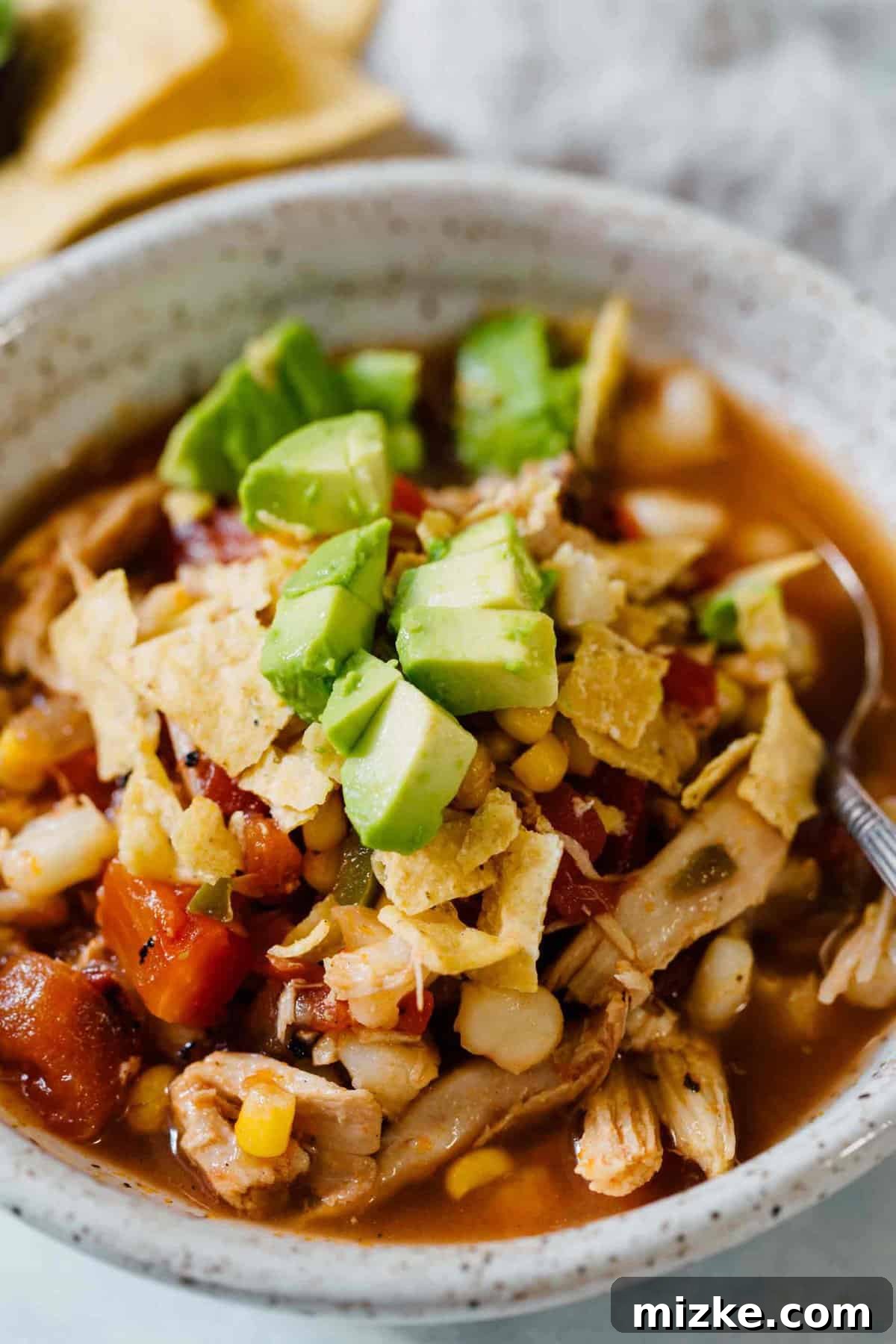 Serving up Stovetop Chicken Tortilla Soup A ladle serving steaming chicken tortilla soup into a ceramic bowl, showing the rich texture and warmth of the dish, ready for toppings.