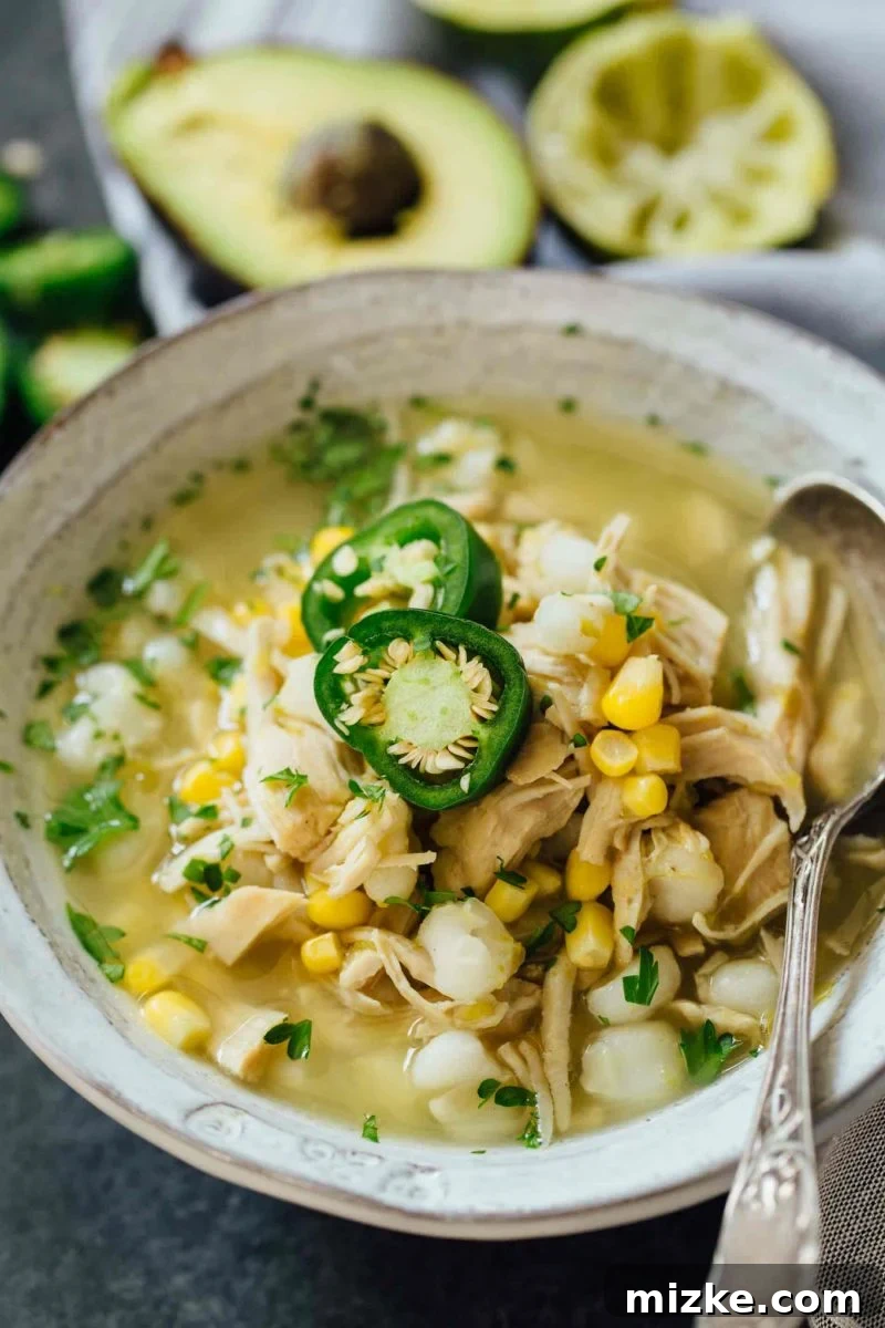 This Instant Pot jalapeño lime chicken soup is beyond flavorful! The spicy broth has hearty additions of hominy, corn, and shredded chicken. Put this all together in less than an hour! Another enticing view of the Instant Pot Jalapeño Lime Chicken Soup in a rustic bowl, garnished with fresh cilantro and lime wedges.