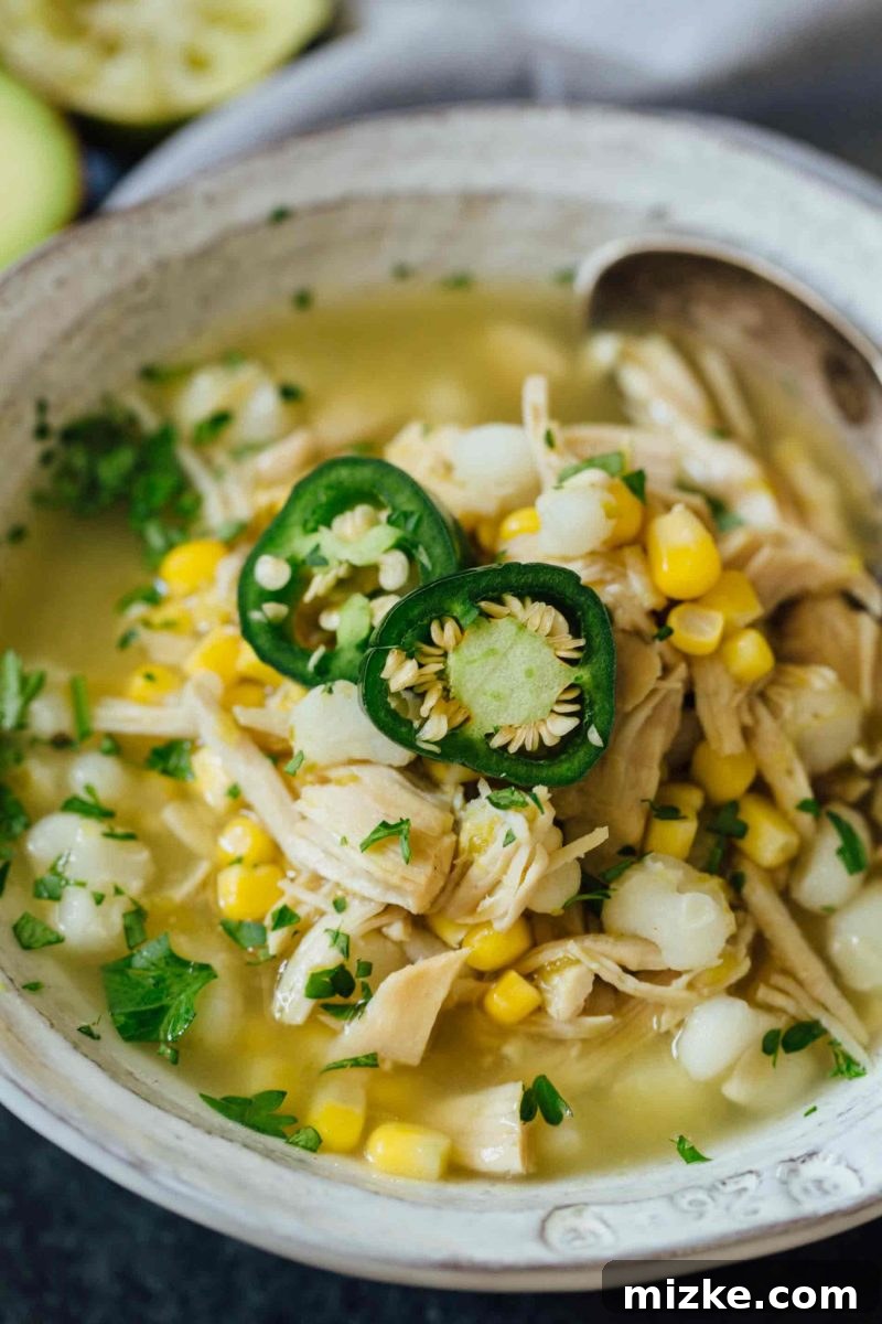 This Instant Pot jalapeño lime chicken soup is beyond flavorful! The spicy broth has hearty additions of hominy, corn, and shredded chicken. Put this all together in less than an hour! Overhead shot of the spicy Instant Pot Jalapeño Lime Chicken Soup, garnished with a sprinkle of fresh cilantro.