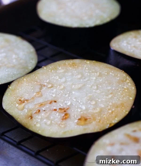 Salting Eggplant for Optimal Texture Eggplant slices sweating out moisture after being salted, a key step for crispy eggplant parmesan.
