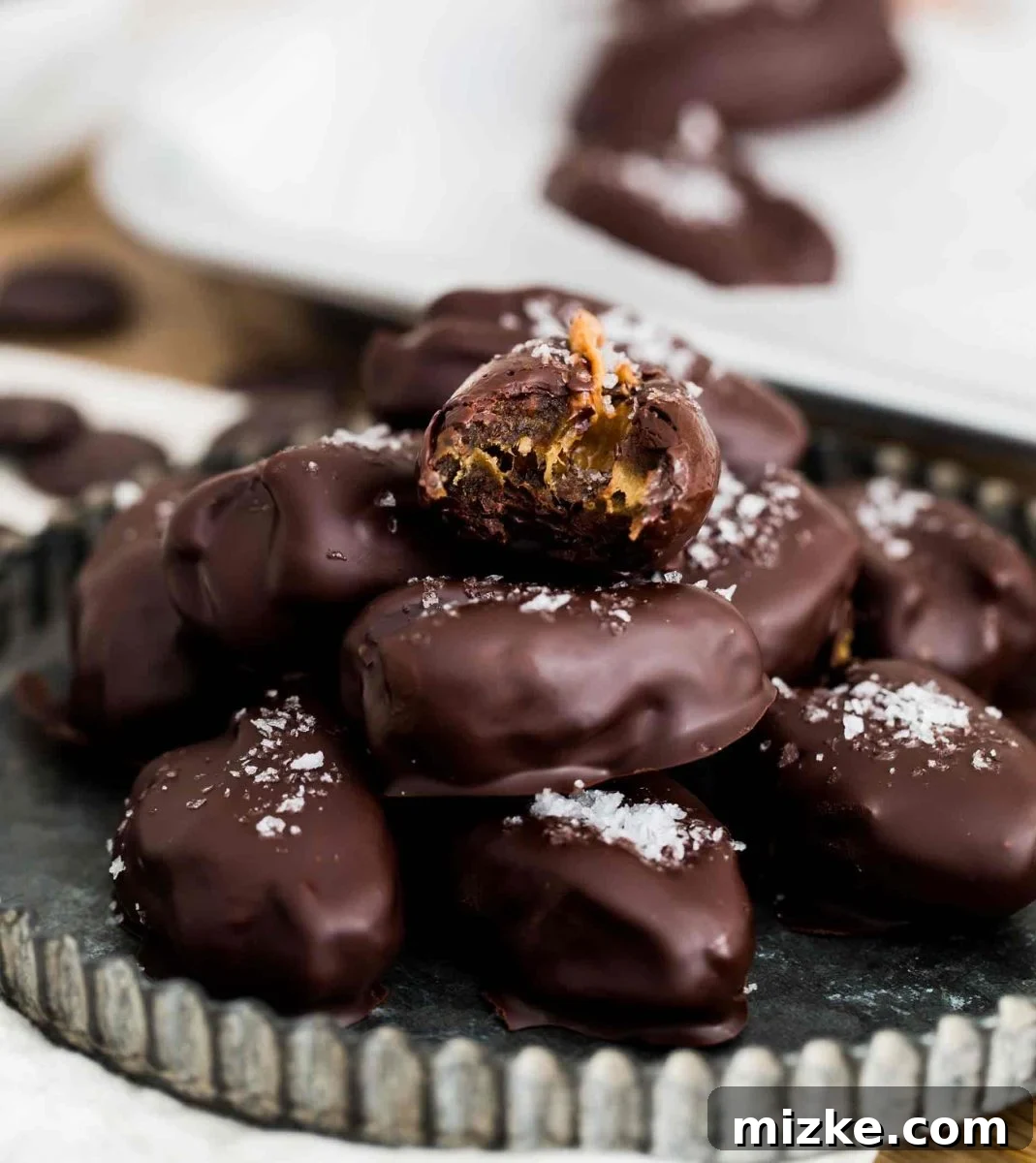 Perfectly Stuffed Medjool Date with Nut Butter and Dark Chocolate A single chocolate covered stuffed date cut in half, revealing the creamy nut butter filling.