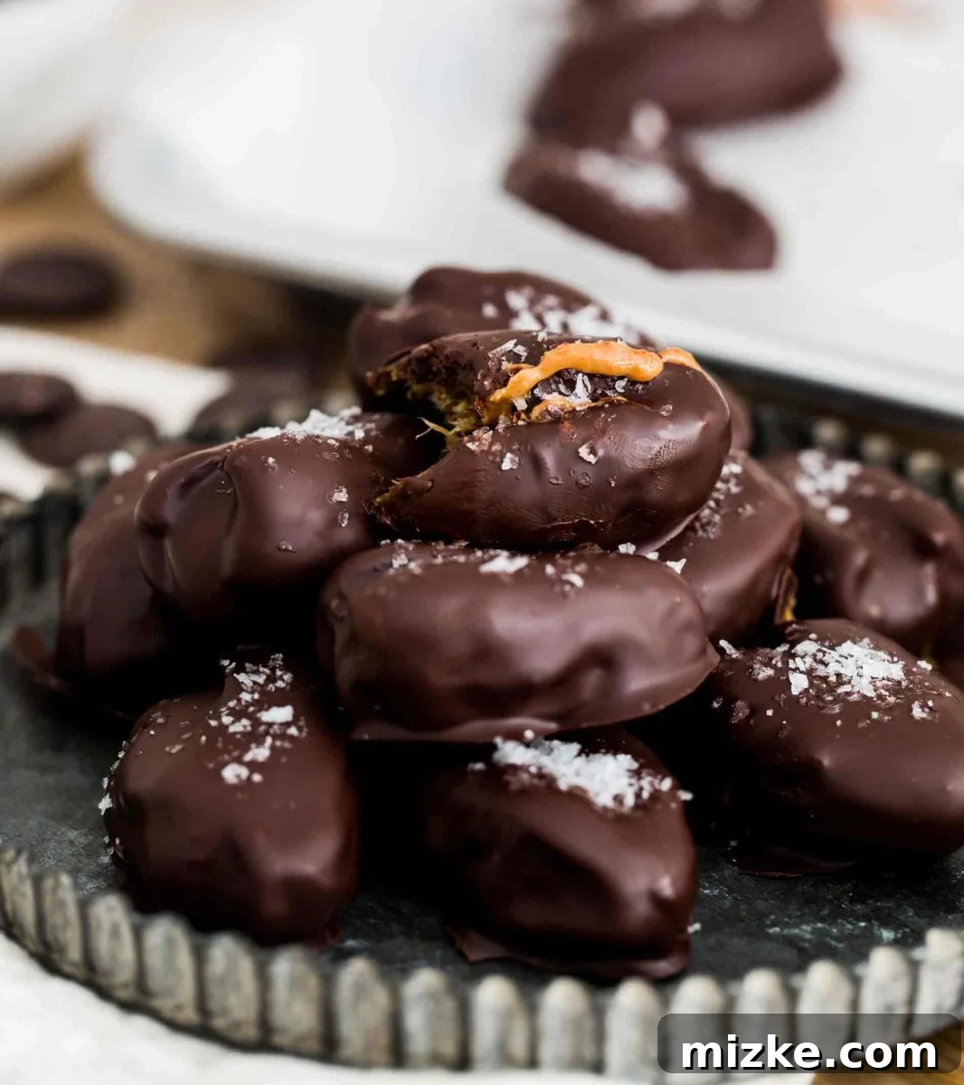 How to Stuff Dates with Nut Butter for Chocolate Coating A hand gently stuffing a Medjool date with creamy peanut butter using a small spoon.
