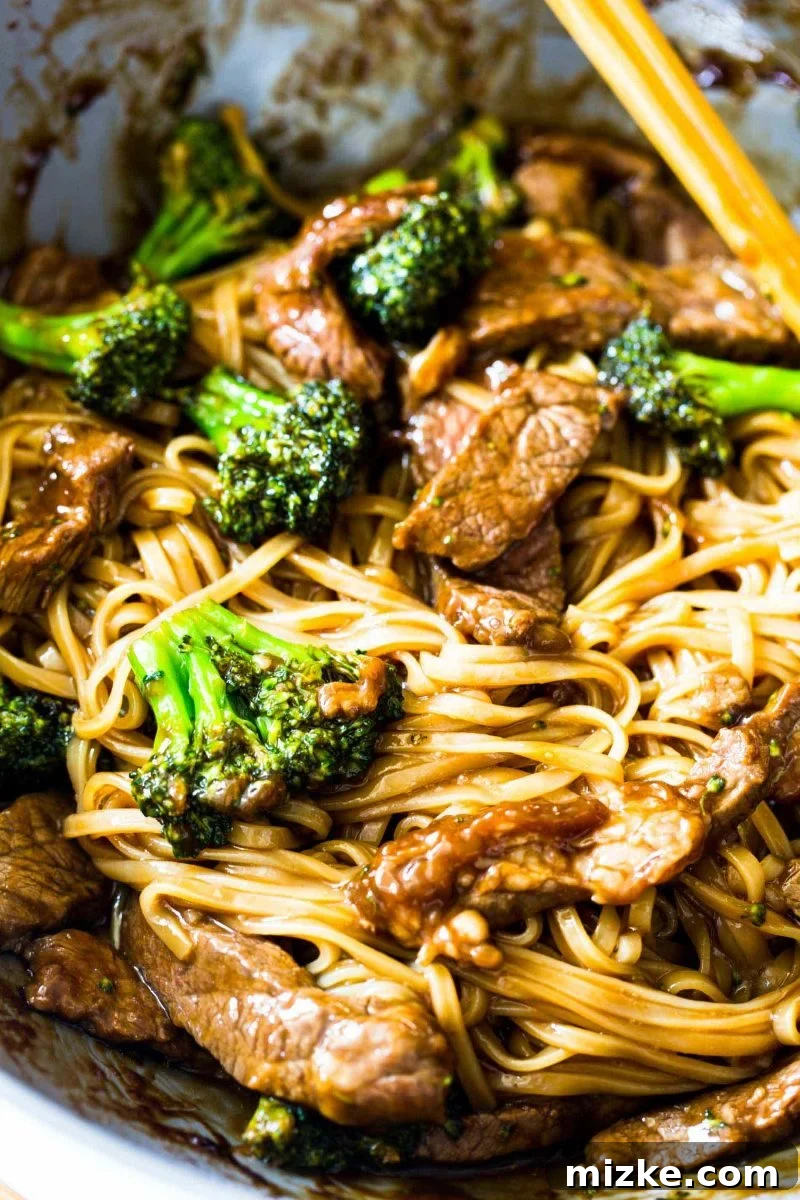 A colorful array of ingredients for Asian Beef and Broccoli Noodles, including thinly sliced beef, fresh broccoli florets, and uncooked rice noodles, ready for preparation. Highlights the simplicity of the components.