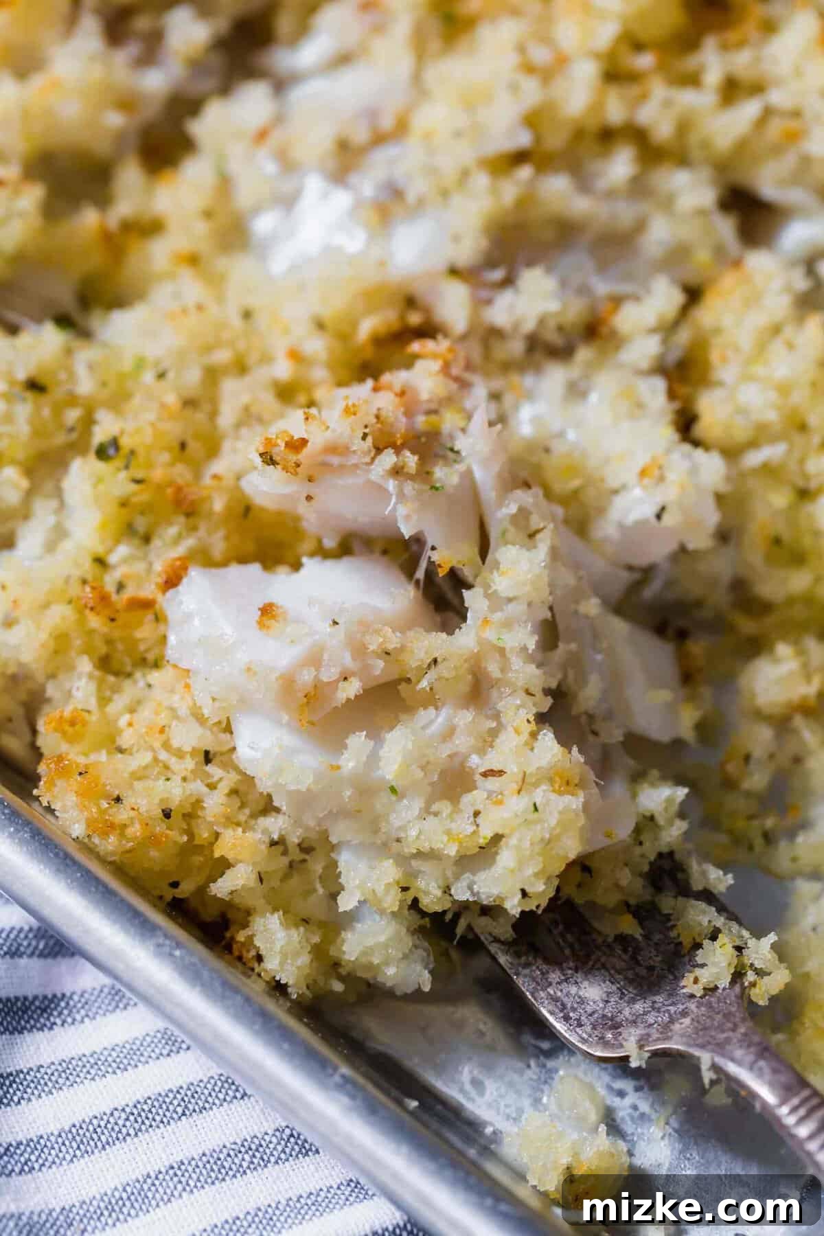 Close-up view of flaky, perfectly cooked haddock on a fork, showing its tender texture