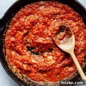 tomato sauce in a cast iron skillet with a wooden spoon