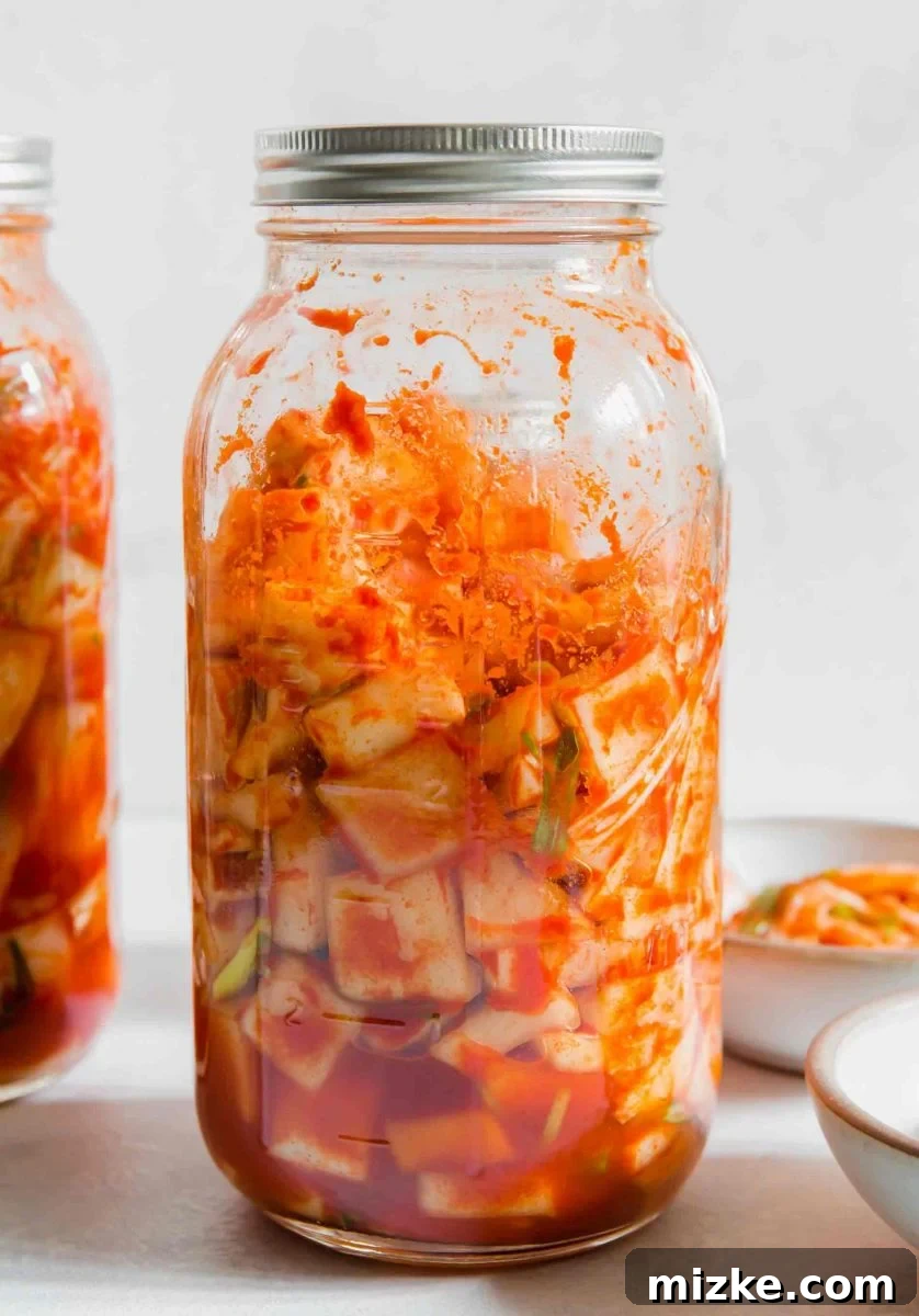 Essential fresh ingredients for crafting authentic homemade Korean kimchi. A selection of fresh, crisp Napa cabbage leaves, vibrant green onions, a whole garlic bulb, and a sweet onion laid out, ready for kimchi preparation