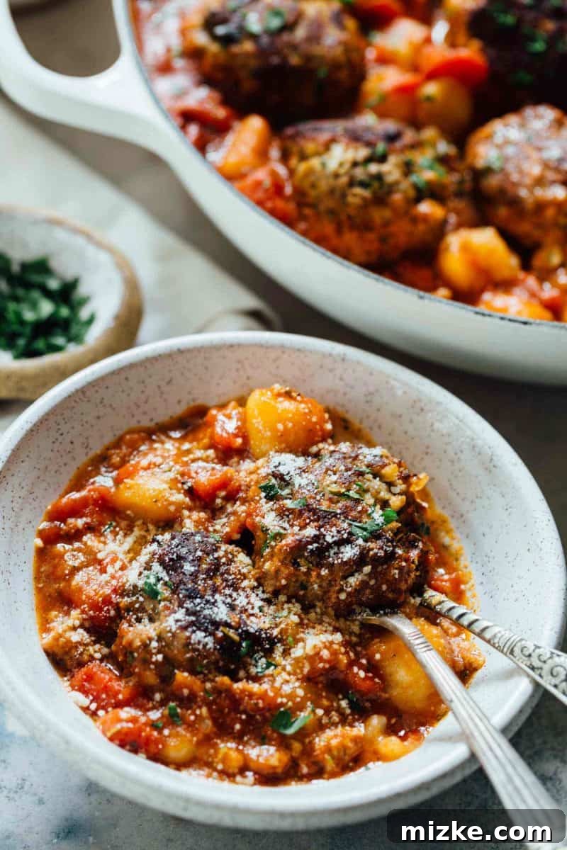 A complete serving of one-skillet cauliflower gnocchi and meatballs, garnished with fresh parsley and Parmesan cheese. A complete serving of one-skillet cauliflower gnocchi and meatballs, garnished with fresh parsley and Parmesan cheese.